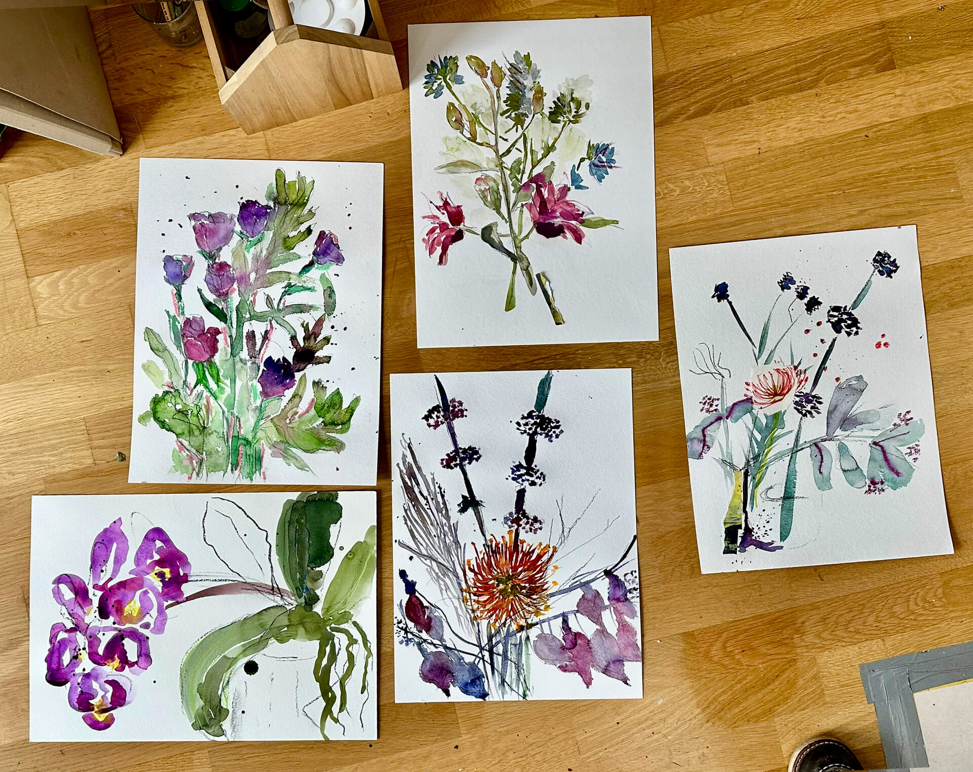 Ergebnisse eines Kurstages: fünf Aquarellbilder mit Blumenmotiven auf dem Atelierboden