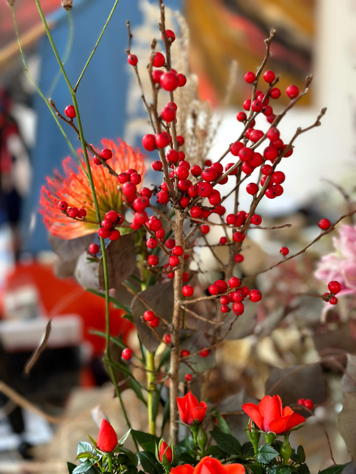 Nahaufnahme eines Blumenarrangements mit Ilex-Beeren und Protea